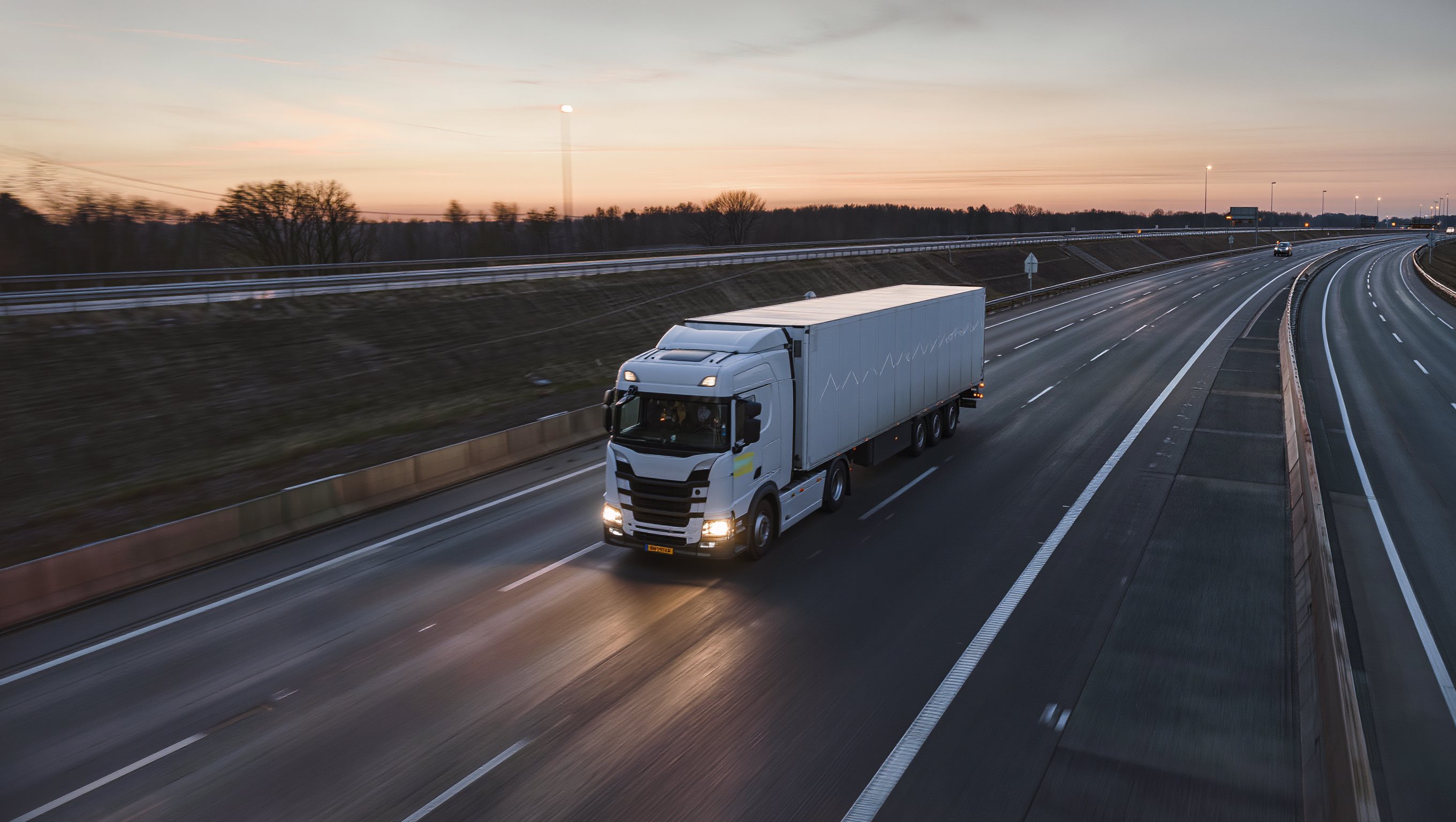 Vrachtwagen met trailer op de snelweg bij schemering